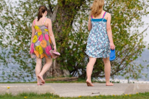 Two women wear floral-print dresses and carry their flip-flops as they walk barefoot along the Howard Temin Lakeshore Path near Lake Mendota at the University of Wisconsin-Madison during spring on May 10, 2011. The area is part of UW-Madison's Lakeshore Nature Preserve.